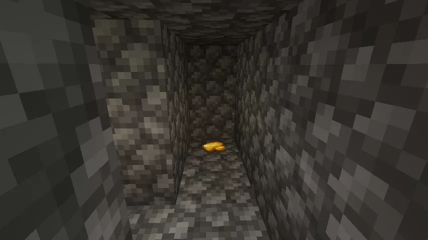 薄暗い丸石の迷路の中で通路の奥の行き止まりに金の原石が落ちている様子