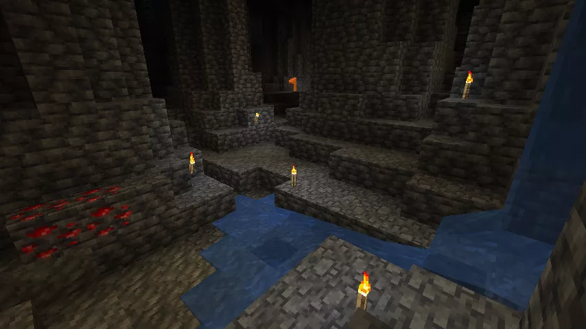 水流の下に1マスの穴がある、松明で照らされた薄暗い深層岩の大空洞内の様子